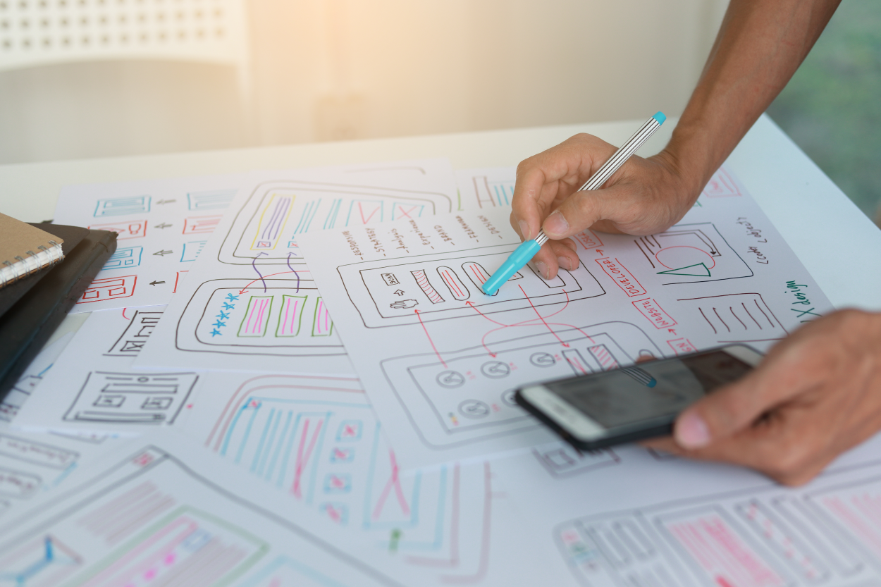 show UX/UI wireframes/ drawings/ post it notes on the wall