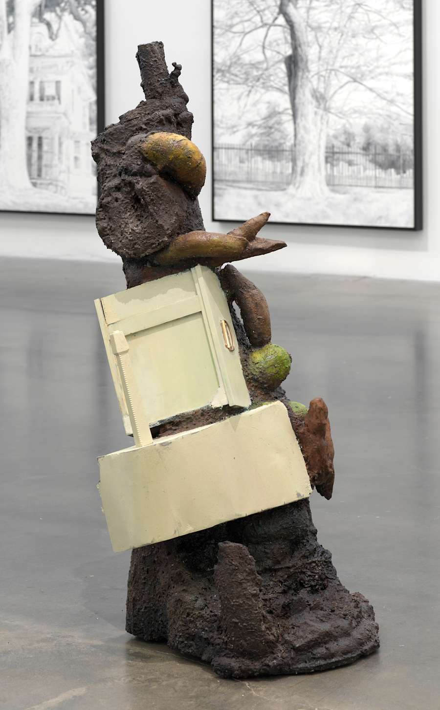 A free standing sculpture resembling a deconstructed piece of cabinetry combined with a tree-like form with fungus protruding from its base.