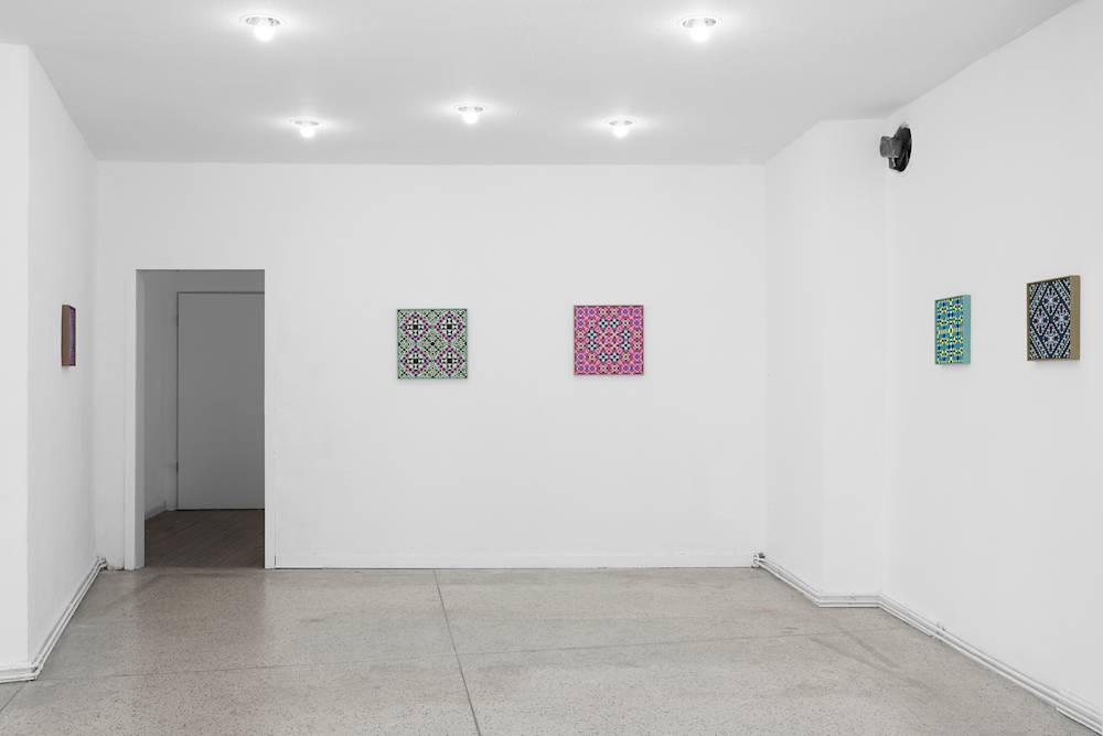 Image of two paintings on a wall, and two paintings, and one painting, on each other side. A hallway opens on the left of the front facing wall.