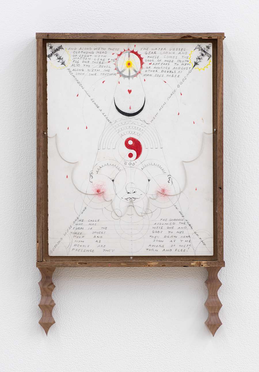 Image of Harry Gould Harvey IV drawing framed in foraged walnut wood, depicting lines of text criss-crossing the drawing, including depictions of a peace sign, yin-yang, and crescent, in addition to a piece of clear plexiglass in the shape of clouds in the bottom corners of the frame, with pieces of carved walnut attached to the bottom of the frame.
