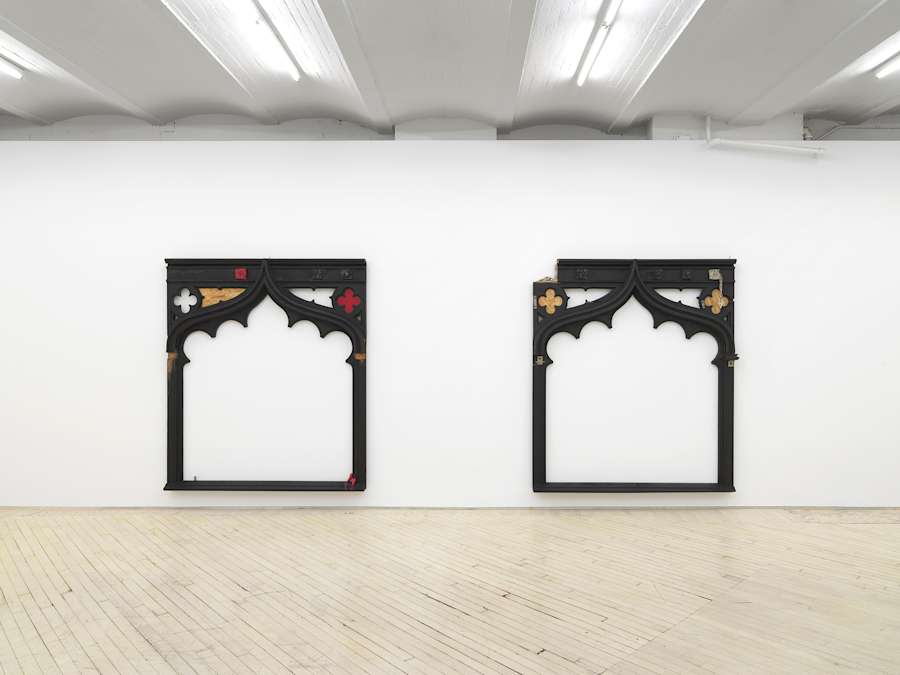 Installation view of two charred wood decorative archways with scalloped edges.