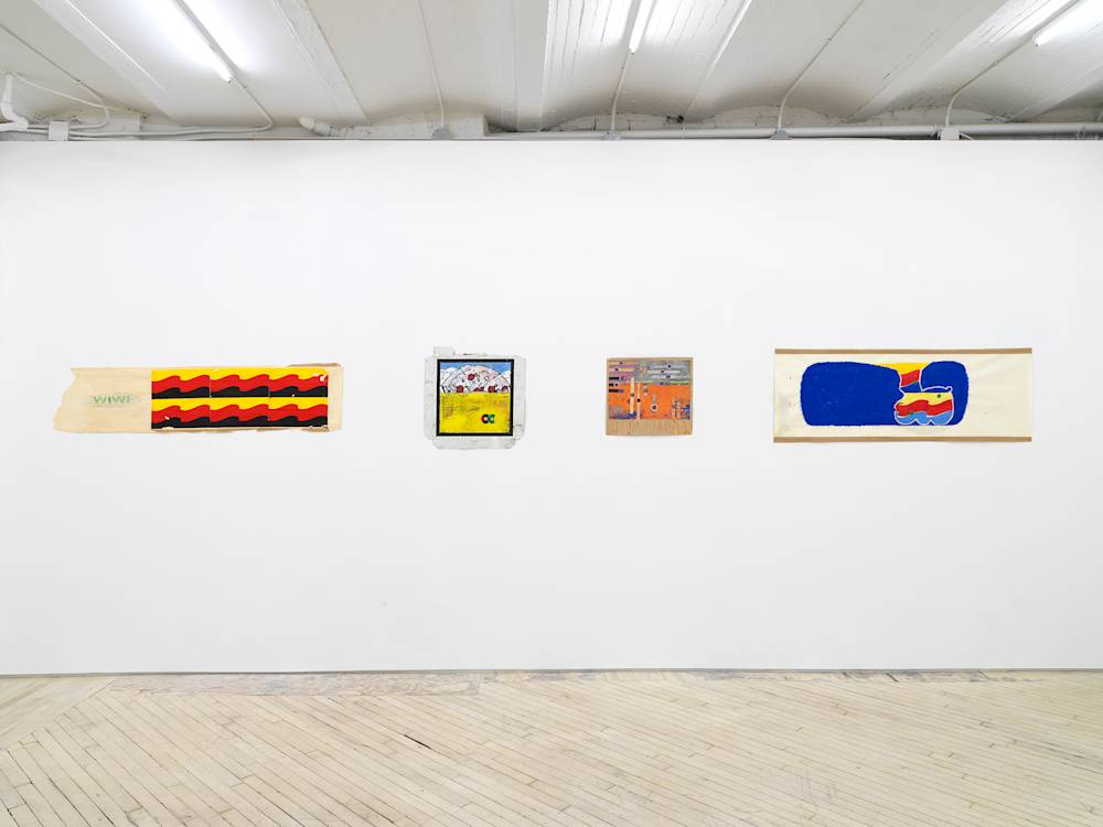 In a gallery space, a series of small works on paper are installed close together on a white wall. The drawing are clustered in a group. The drawings depict abstracted, cartoon-like character scenes. The sizes of the paper vary in length and proportion. The drawing on the left depicts a wave pattern in the color of a German flag. The drawing in the center is done on top of a pizza box.