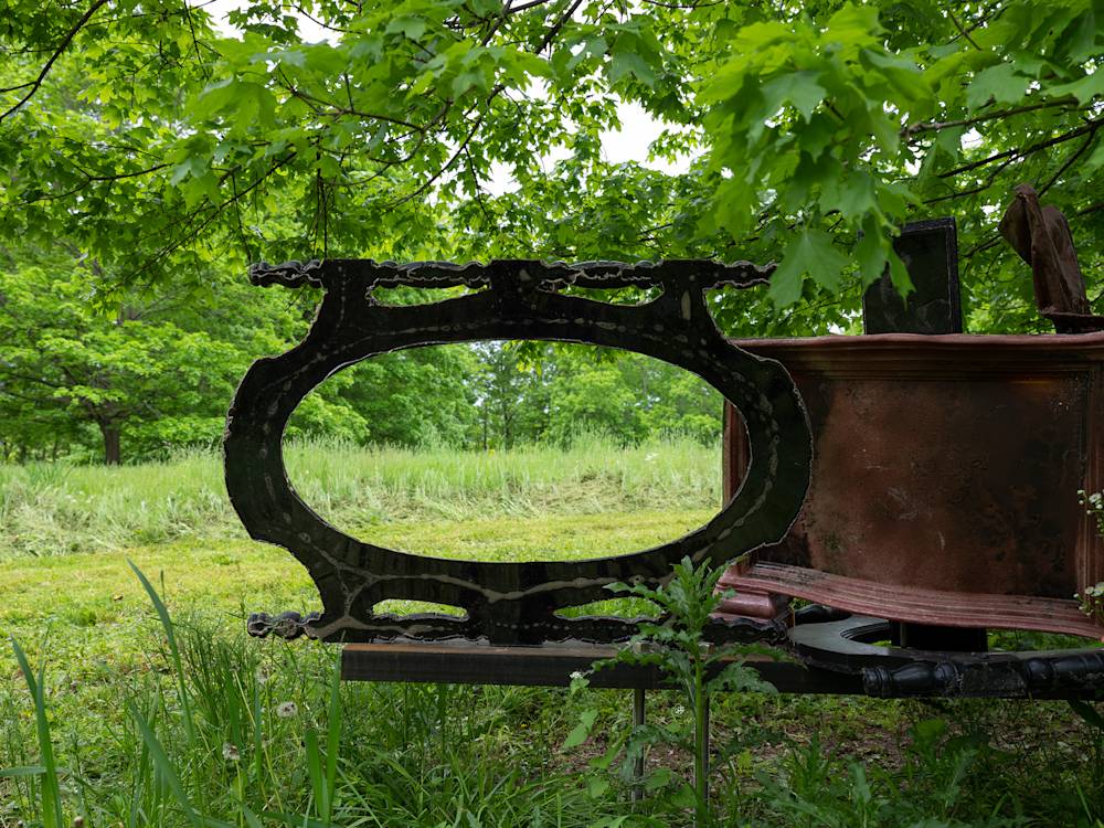 A large tree surrounded by numerous abstract sculptures resembling furniture.
