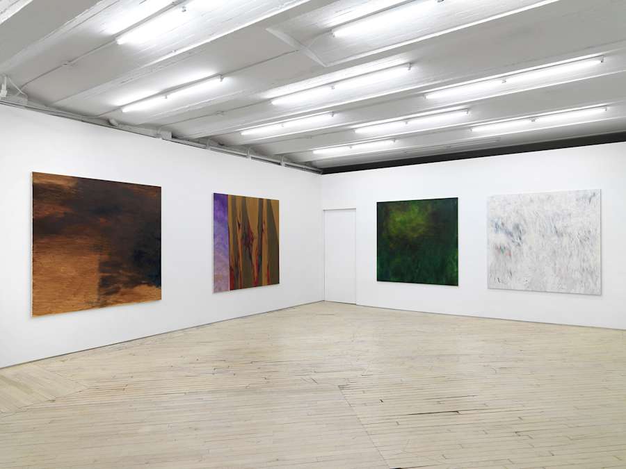 Four large, square, abstract paintings evenly spaced apart from one another in a large gallery space.