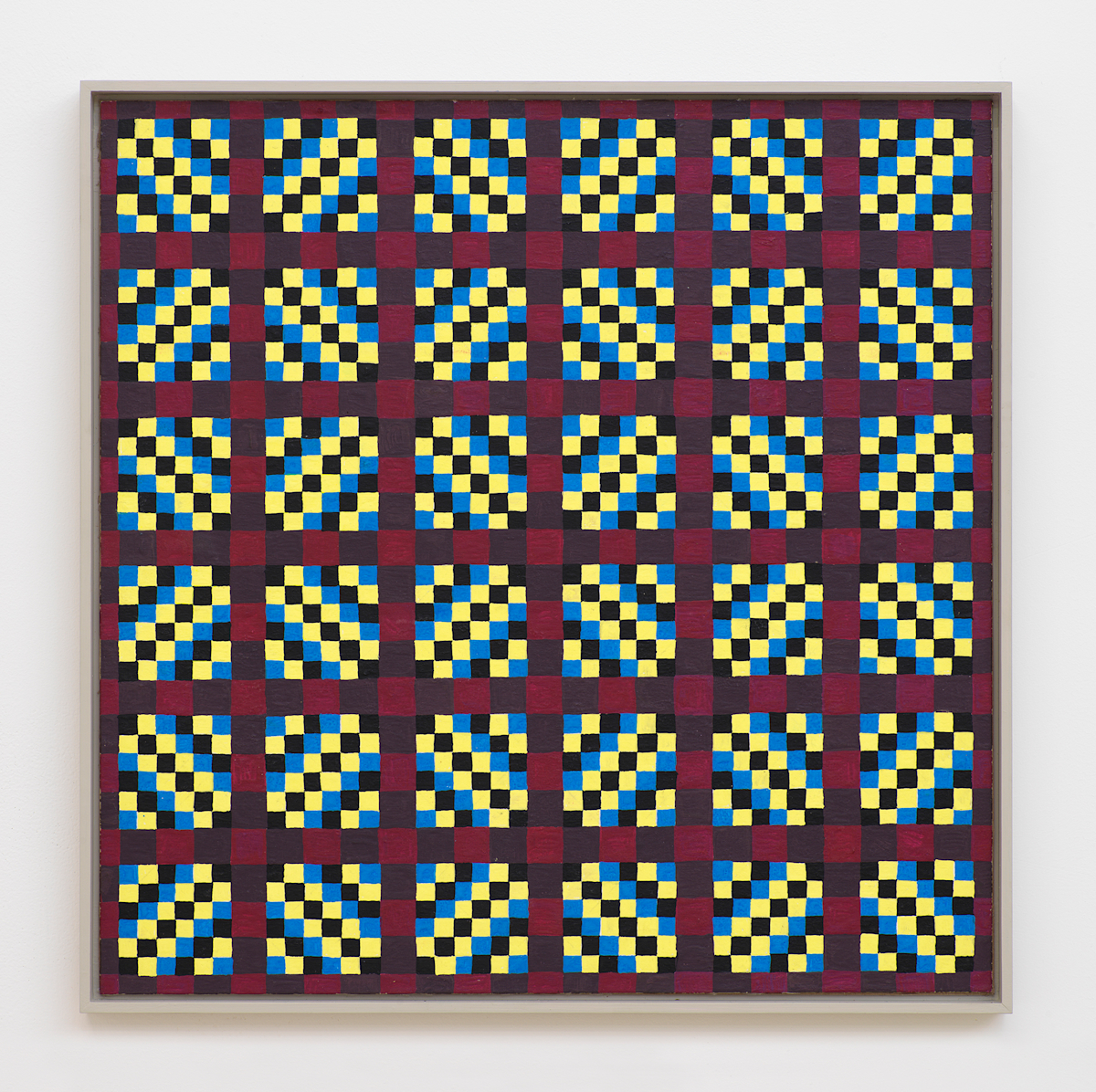 On a white wall a square painting depicting a grid of crisscrossing lines generating many rectangles, and triangles. The dominant colors are hues of maroon, black, blue, and yellow. The frame is painted gray.