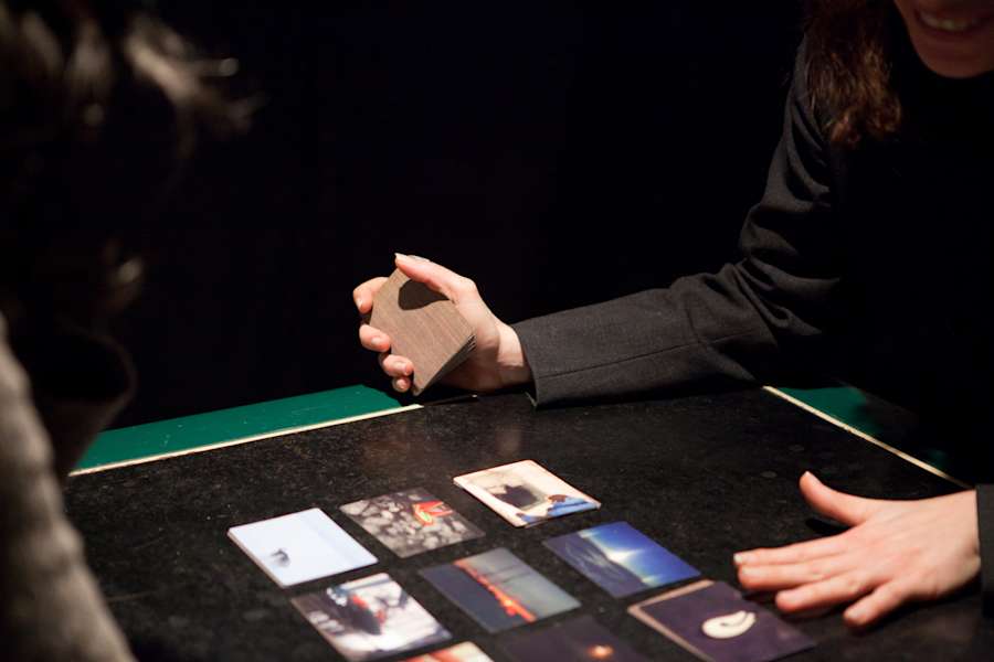A collapsible table with multiple cards depicting blurred photographs. A pair of hands are handling the cards.