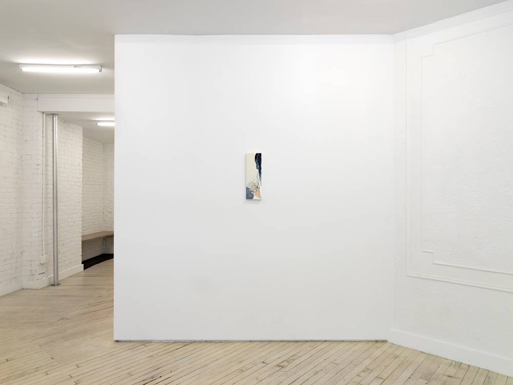 Installation view of a small vertical painting on a white wall with a hallway on the left side of the wall.