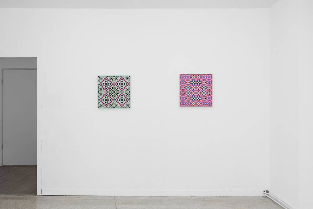 Image of two grid paintings next to each other on a wall. A hallway opens on the left.