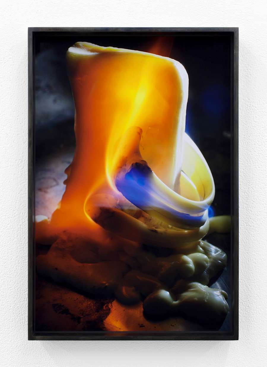 Something like a bone or bar of soap stands erect in the center of the image, pierced with two large rings near the base of the object. The object is on fire and glowing blue-orange-red.