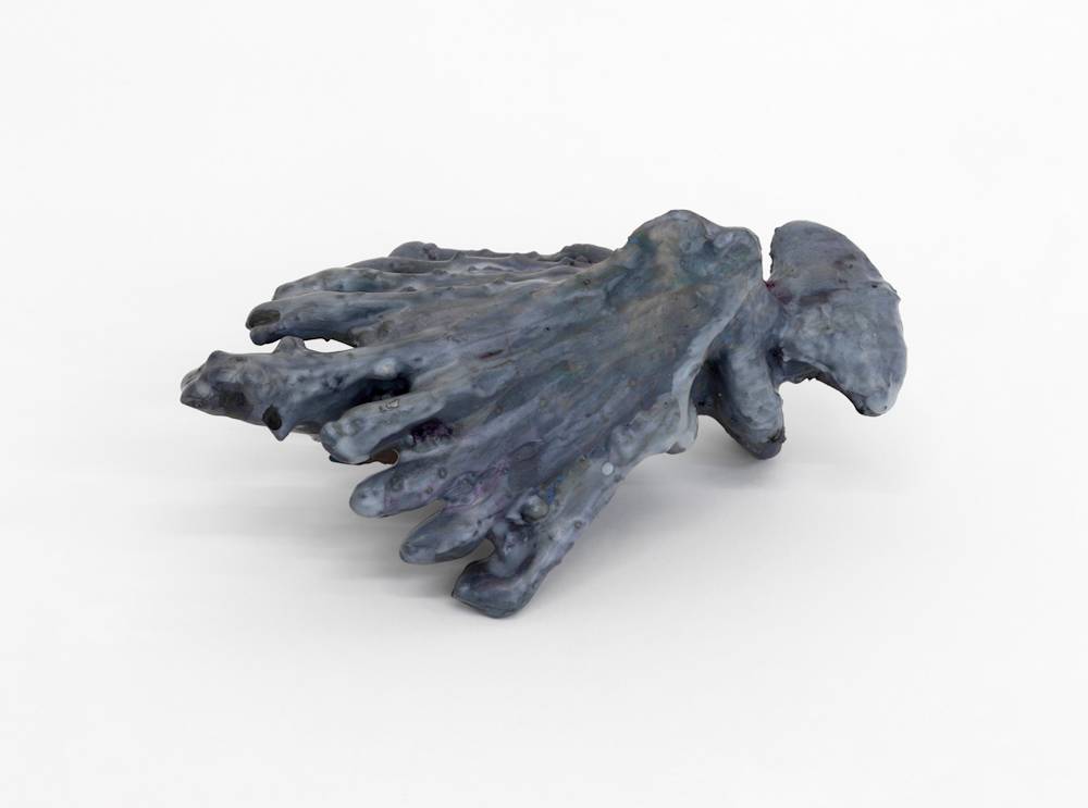 A small abstract sculpture resembling organic material . It is gray.