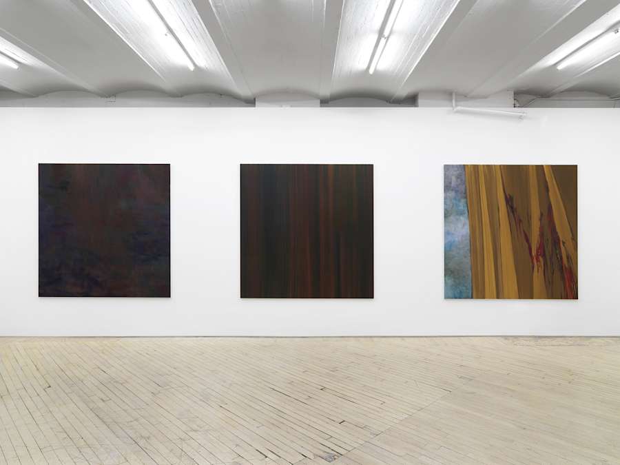 Three large, square, abstract paintings hung evenly spaced on a long gallery wall.