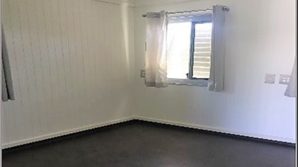 bedroom with wooden floors, white walls and window.