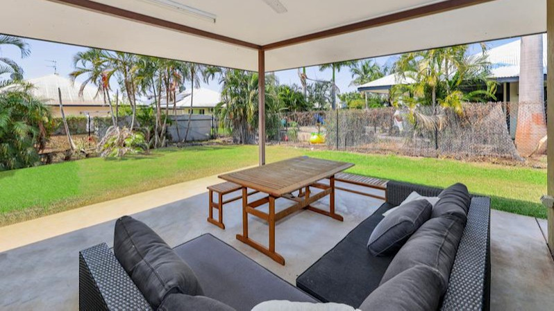 Outdoor patio with wrap around lounge and wooden table and bench.