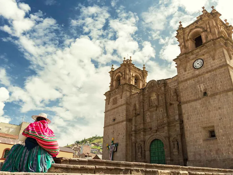 Woman-with-keperina-bag-on-her-back-sitting-on-the-steps-of-the-Cathedral-of-Puno-Peru