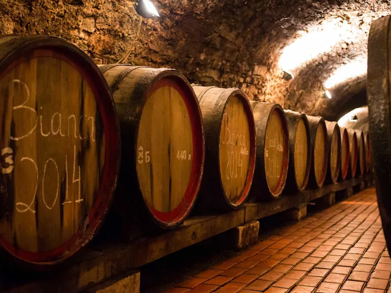 traditional-wooden-barrels-with-wine-in-a-vault-lined-up-in-cool-and-dark-cellar-in-Italy-Porto-Portugal