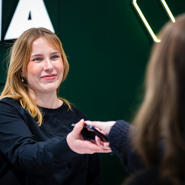 Myyjä ojentaa korjatun puhelimen asiakkaalle