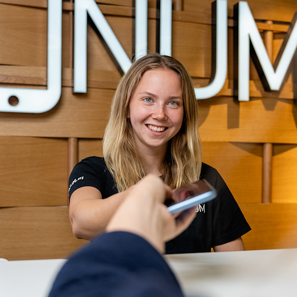 Fonum naistyöntekijä ojentaa huollettua puhelinta asiakkaalle