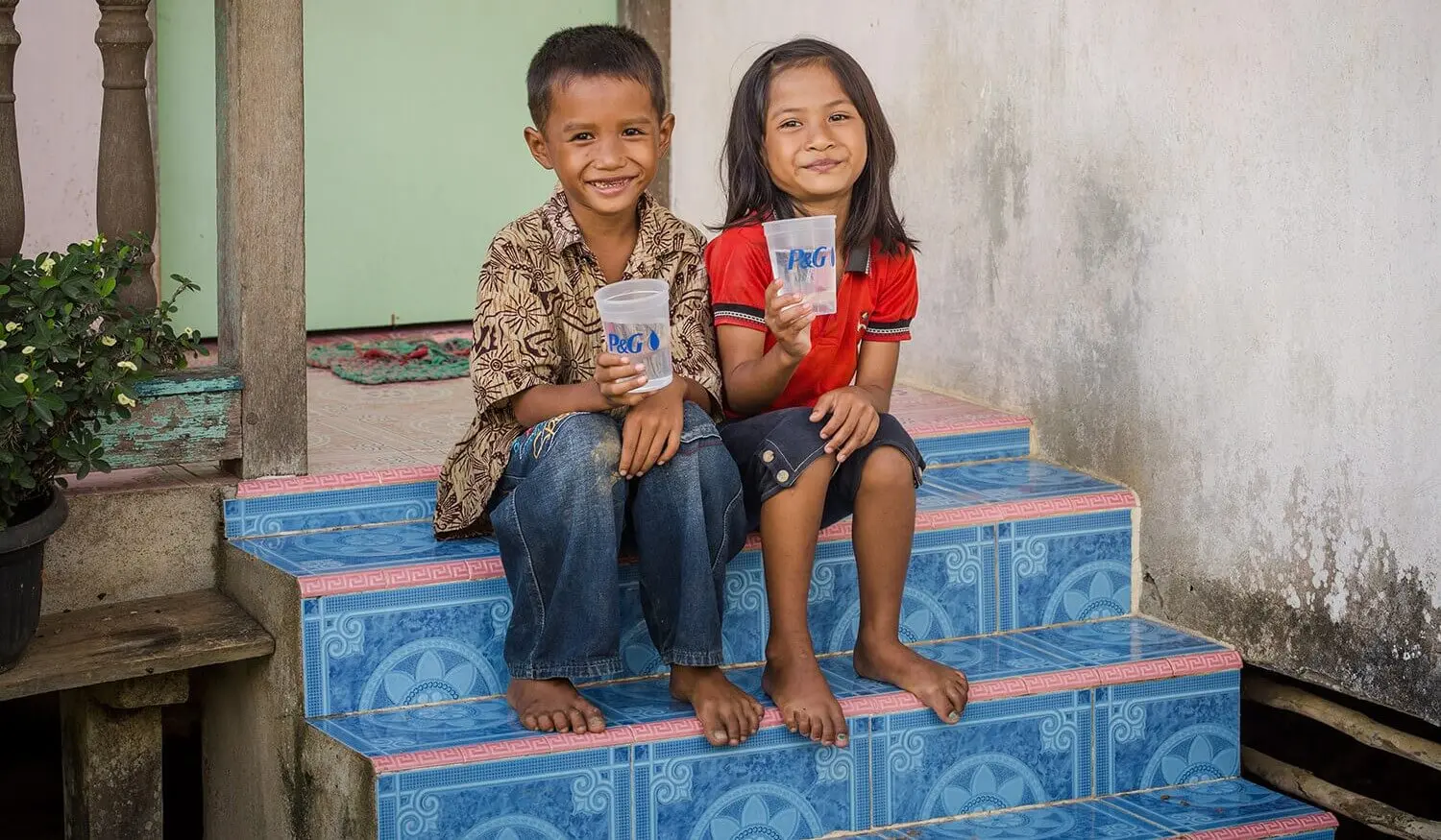 Children smiling and holding a glass of purified water