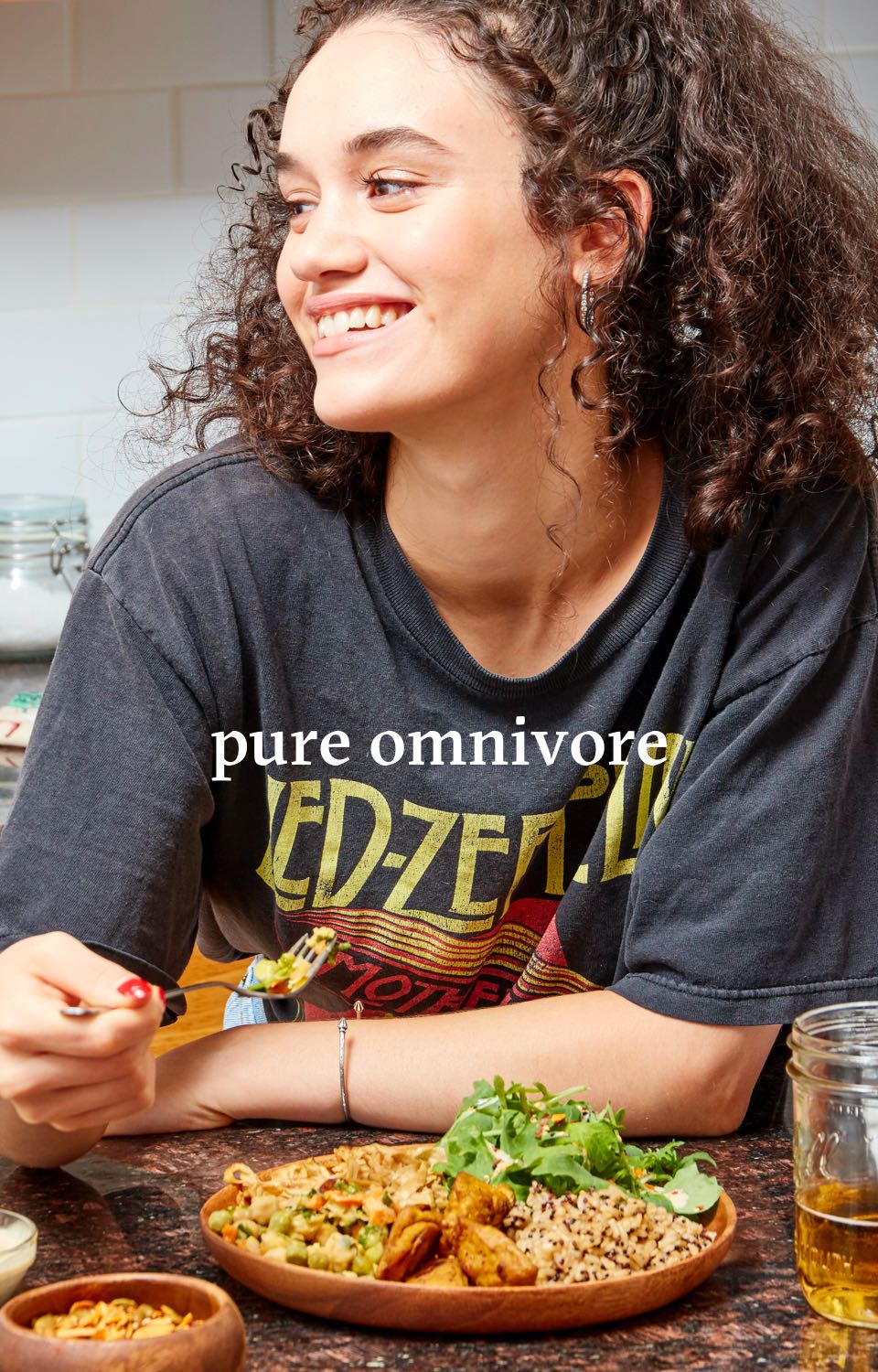 Woman smiling and eating a plate of food. Headline reads Pure Omnivores