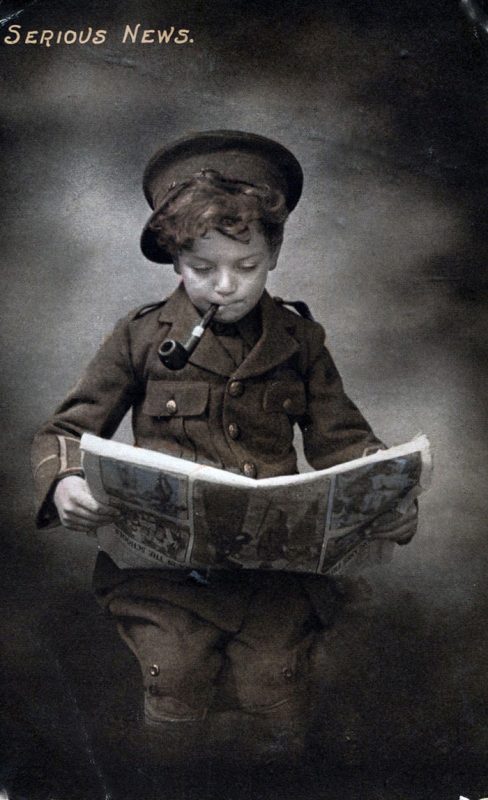boy in military uniform reading a newspaper