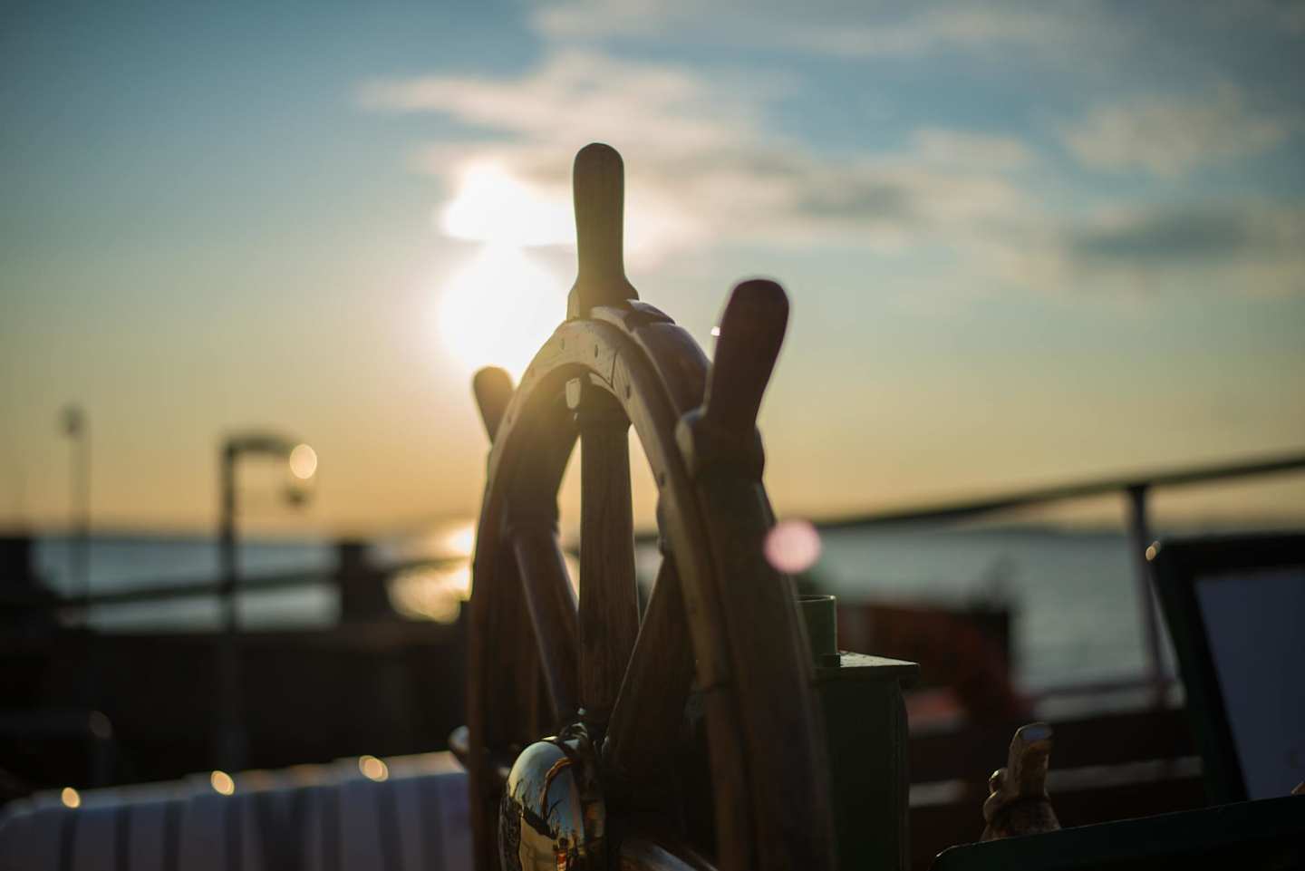 Close up of a brown steering wheel on a ship at sunset