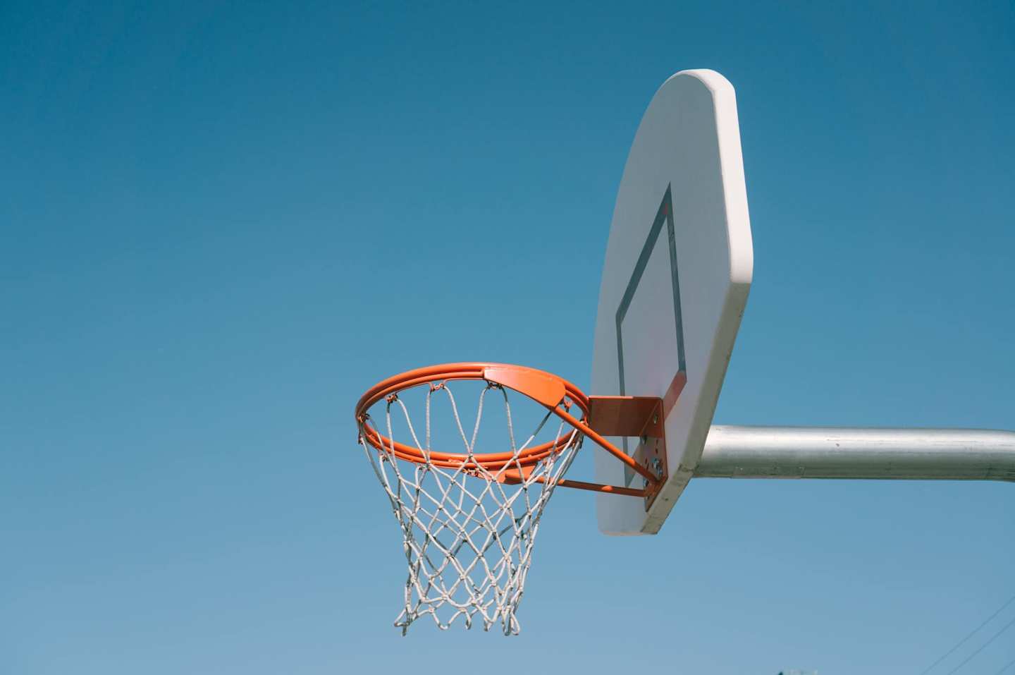 A basketball hoop and a backboard against a blue sky on a sunny day in the US