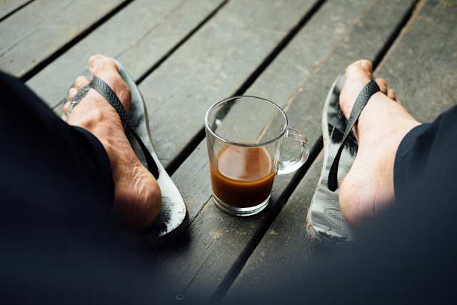 Person's feet in flip flops and a cup of coffee