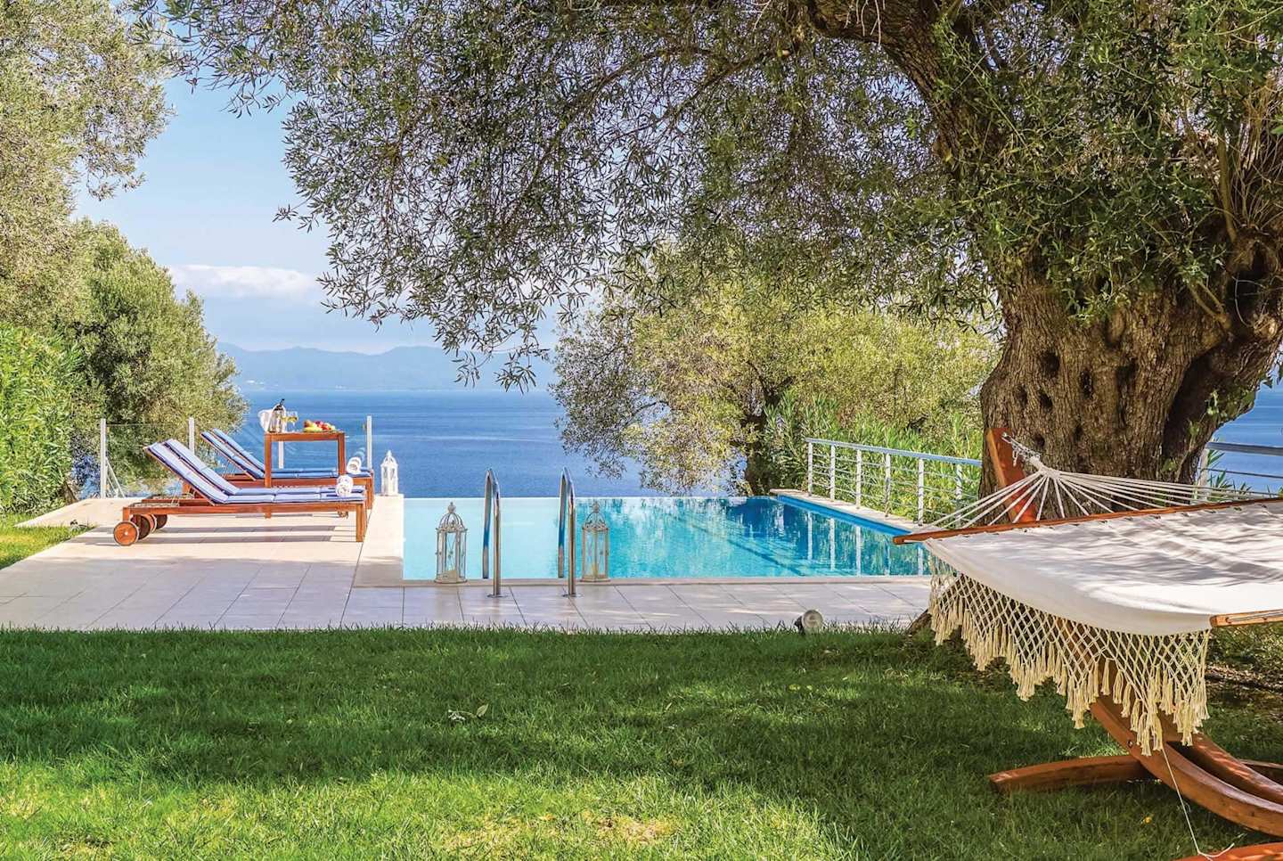 Deck chairs and an infinity pool overlooking the sea at Galini's Heart, Plum Guide home in Greece