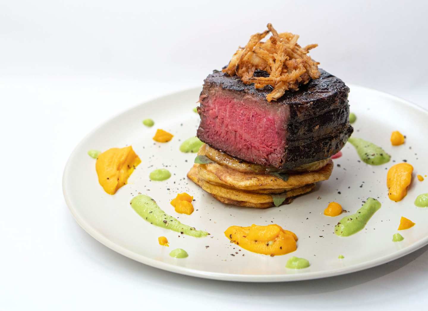 Steak rump with fried onions and sliced potato at a fancy restaurant