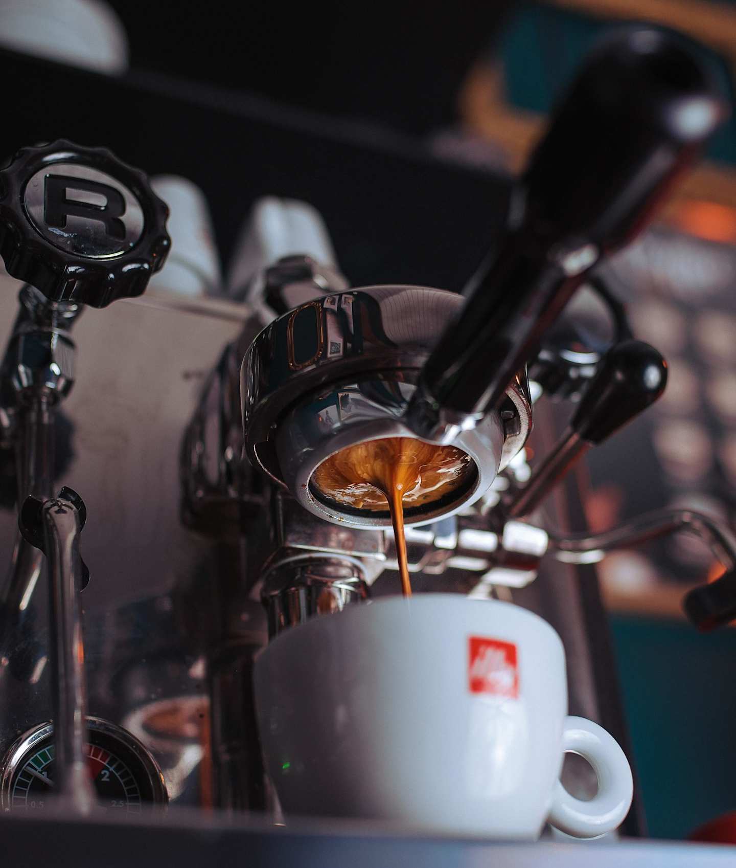 A white mug being filled with coffee in a coffee machine