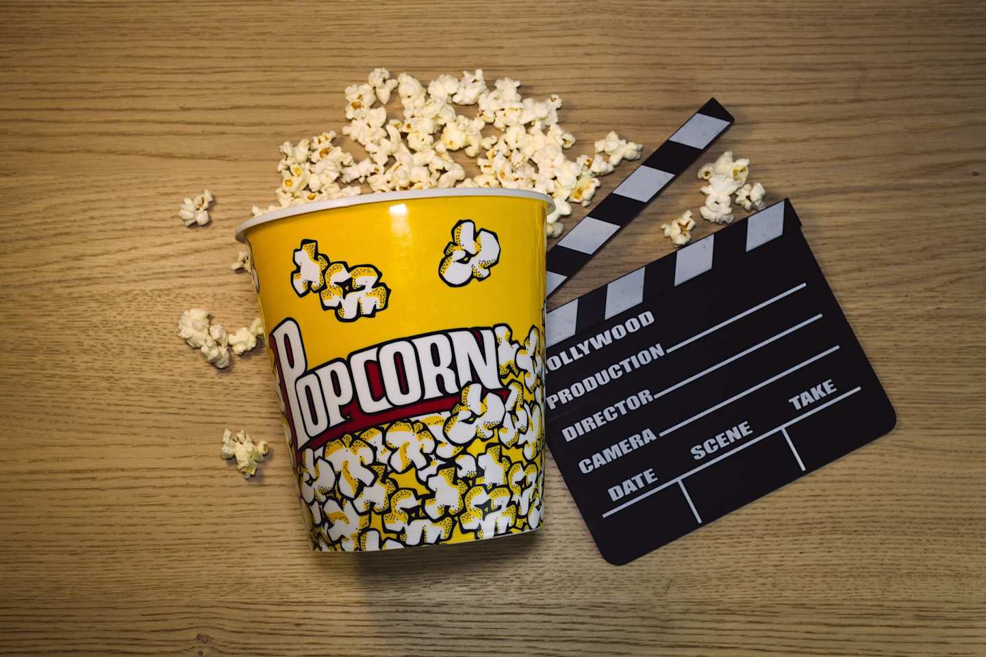 Popcorn and black clapperboard on table
