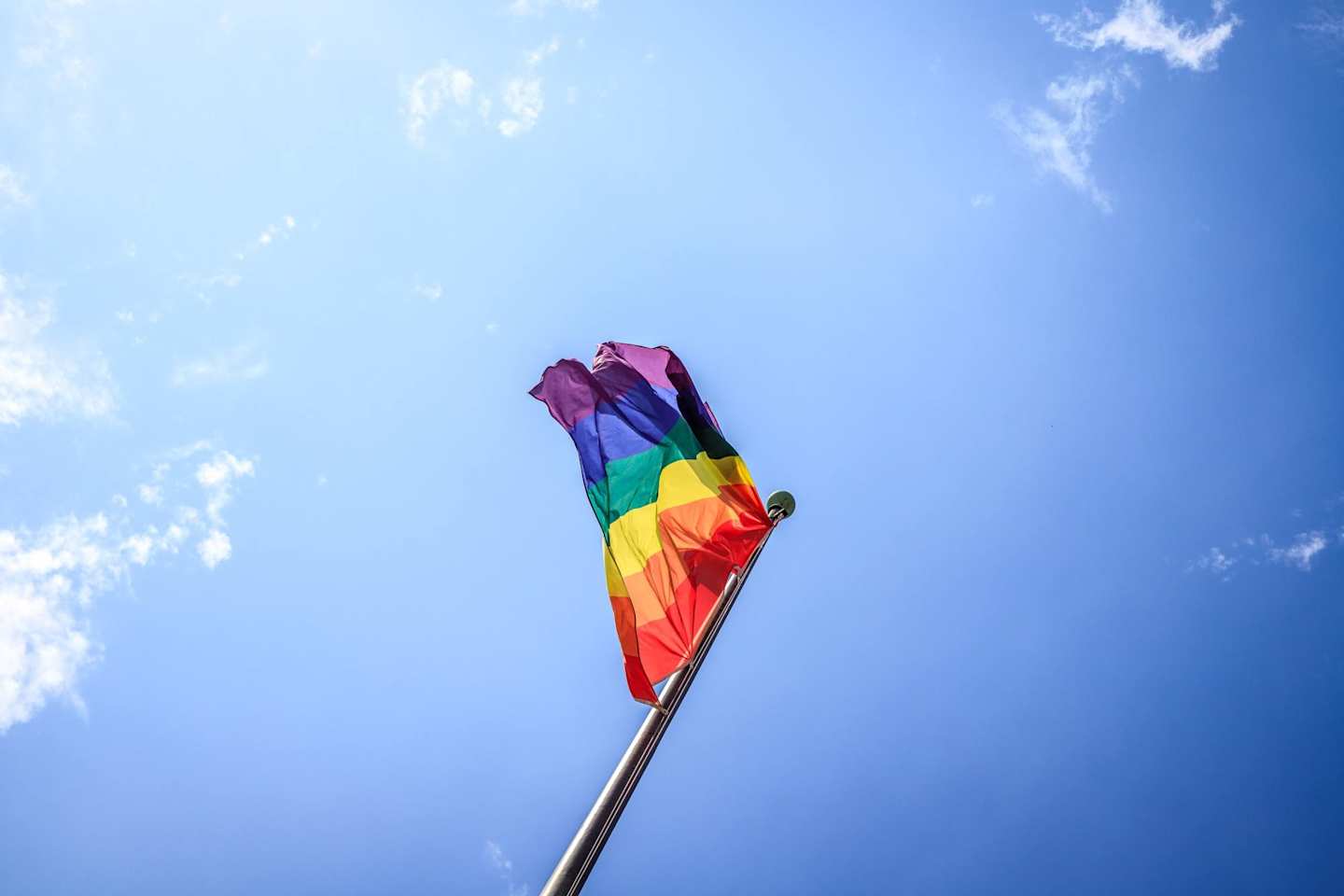 Rainbow-coloured Pride flag waving in the wind on a tall flag pole
