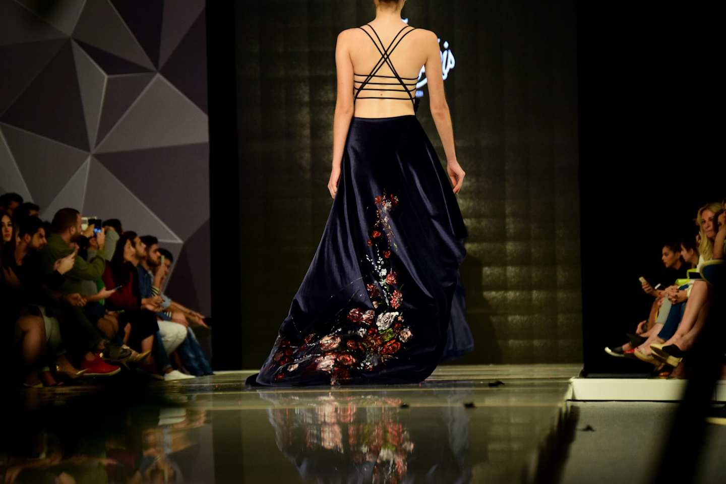 Woman in a fashionable blue dress walking on a catwalk