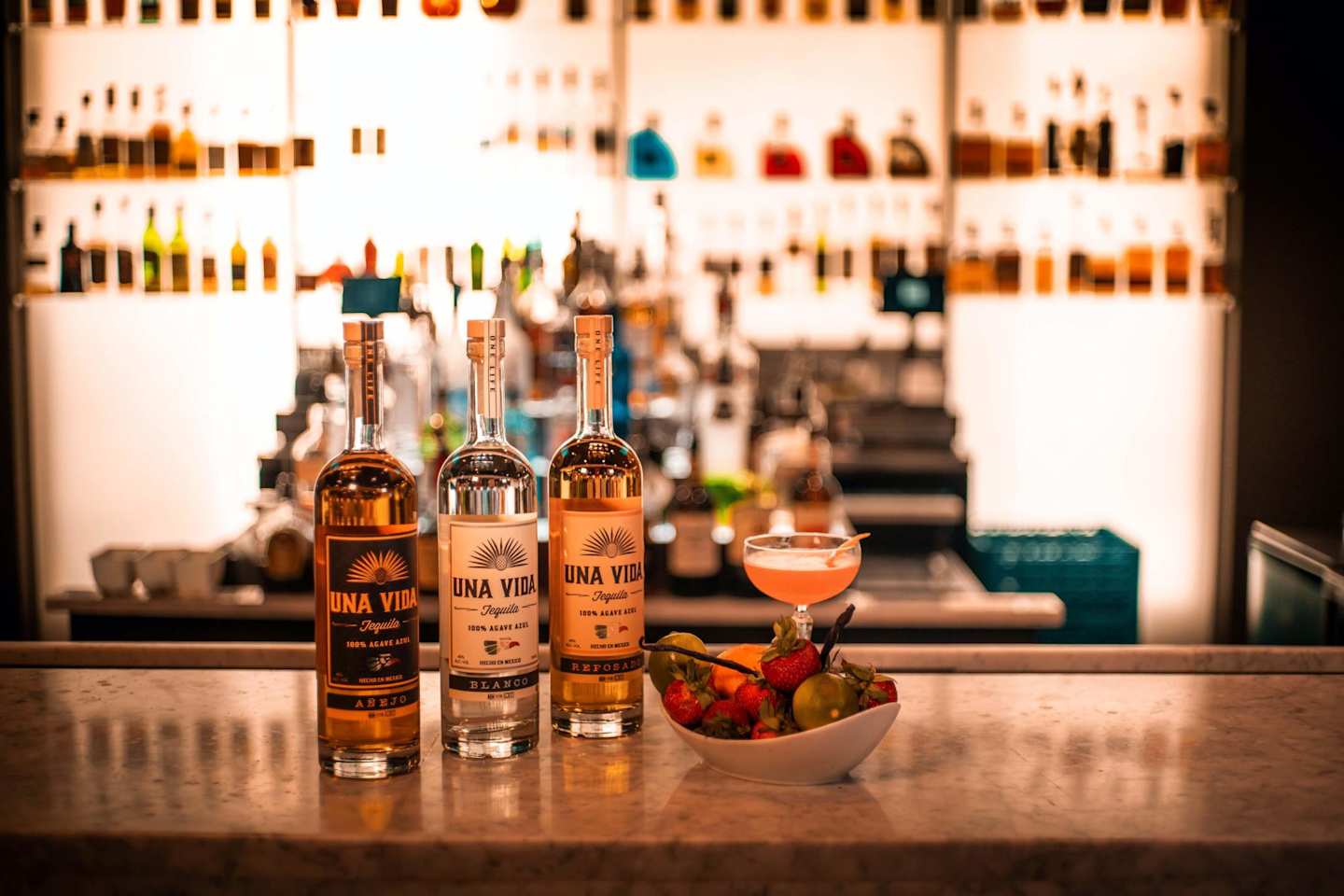 Bottles lined up at a bar next to a cocktail