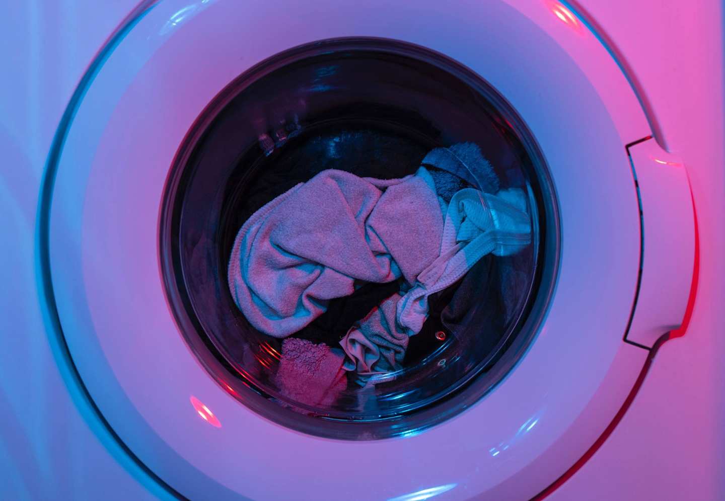 A close up view of clothes in a washing machine with purple and blue lights