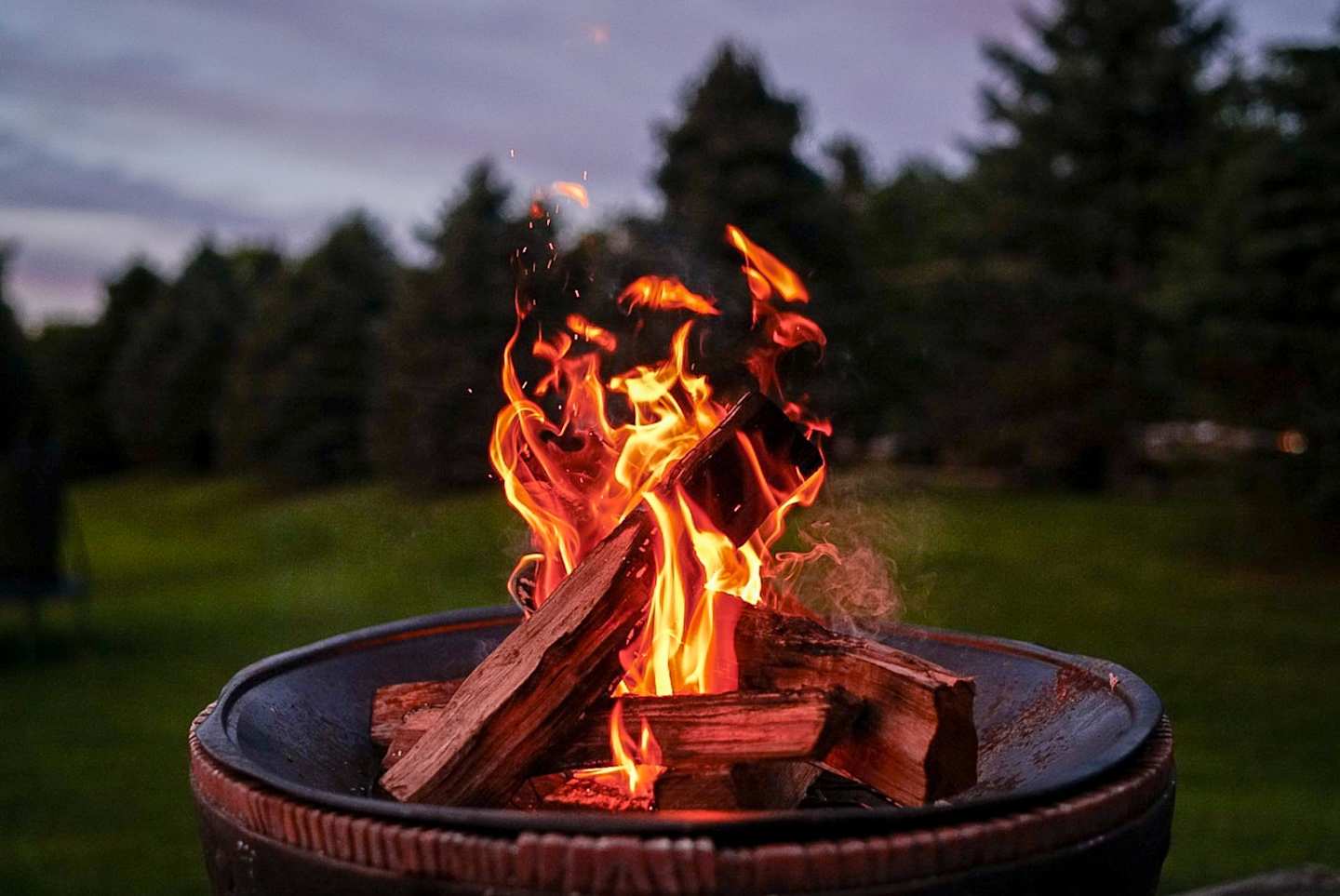 A close up view of wood burning in a fire pit in the evening