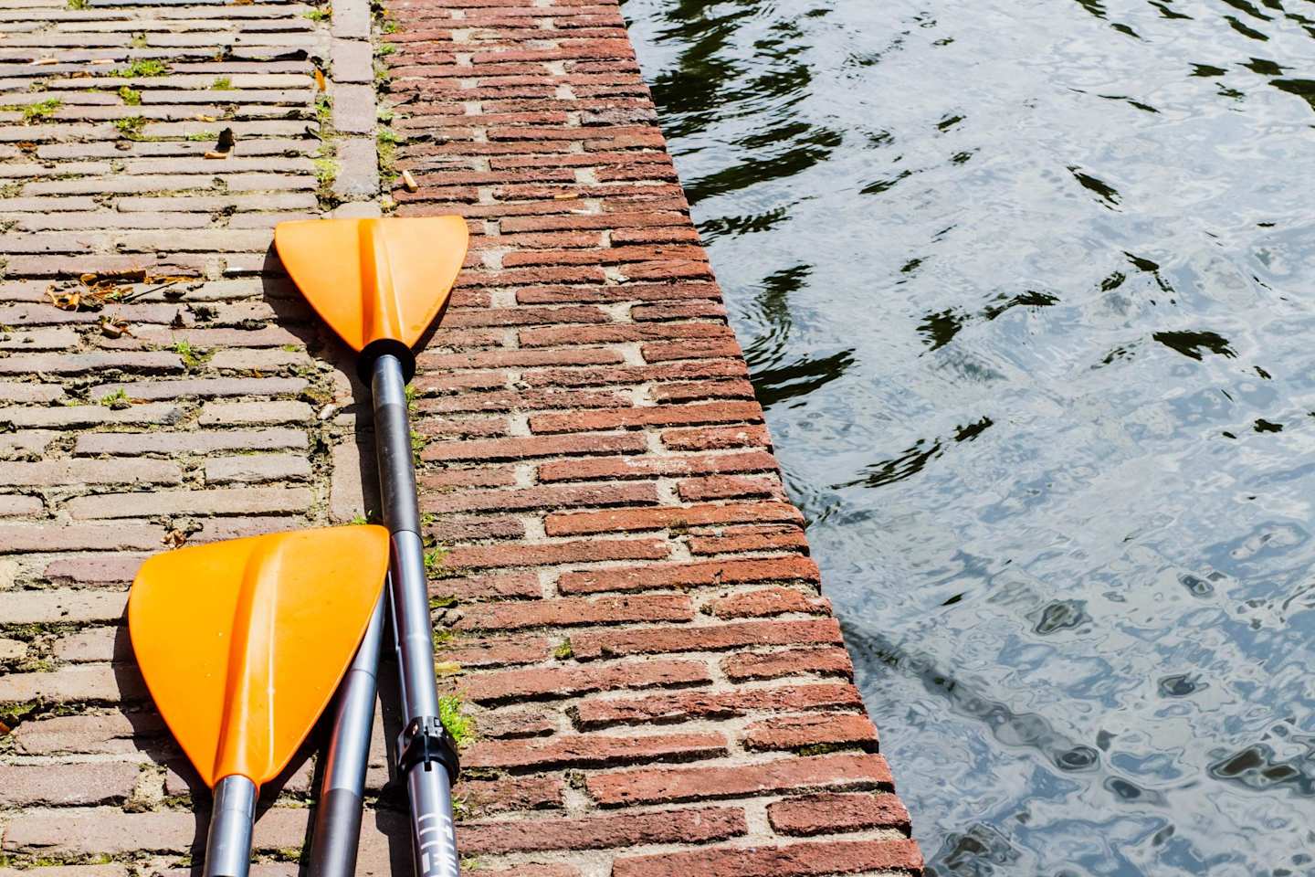 Orange oars on a wall next to a lake