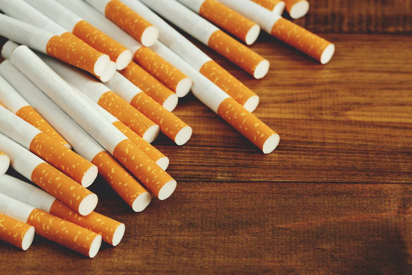 A collection of unused cigarettes on a wooden table