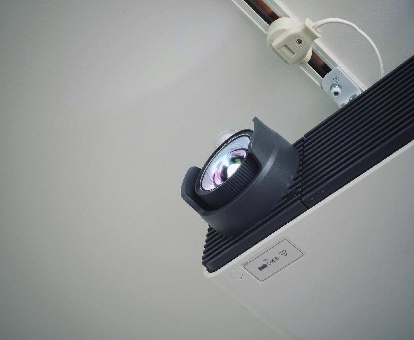 A white projector fixed to the ceiling in a home cinema room