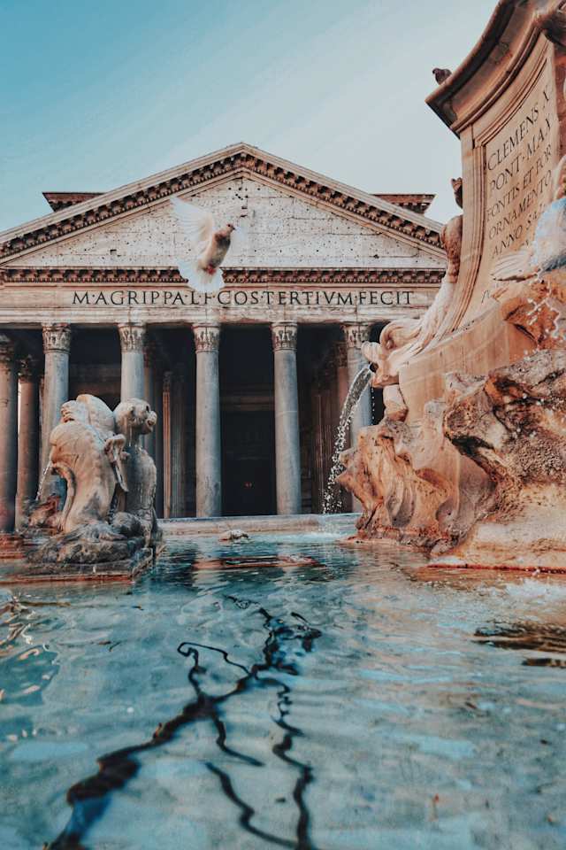 The Roman Pantheon behind a large fountain in Rome, Italy