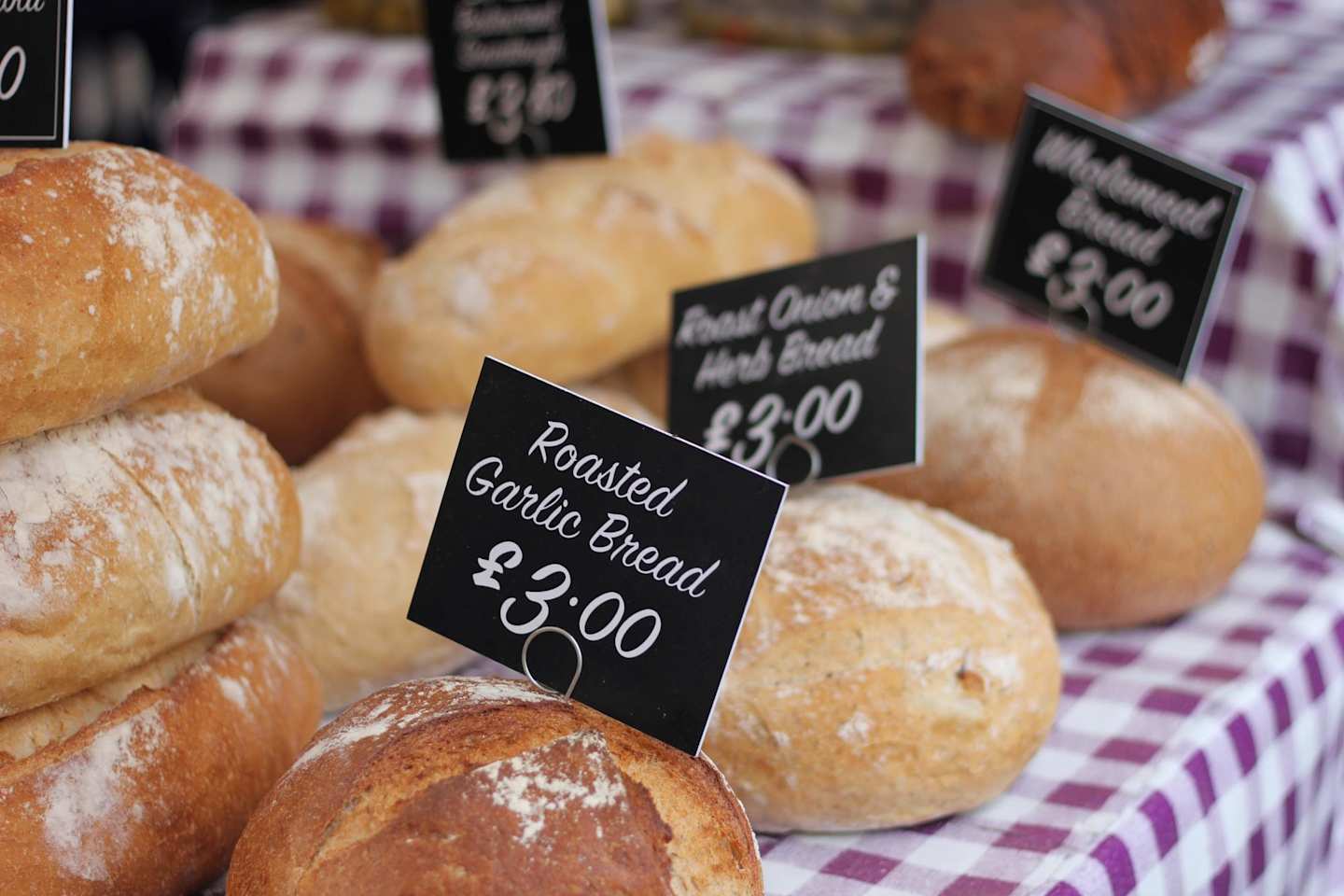 Loaves of bread on red and white gingham table cloth at market