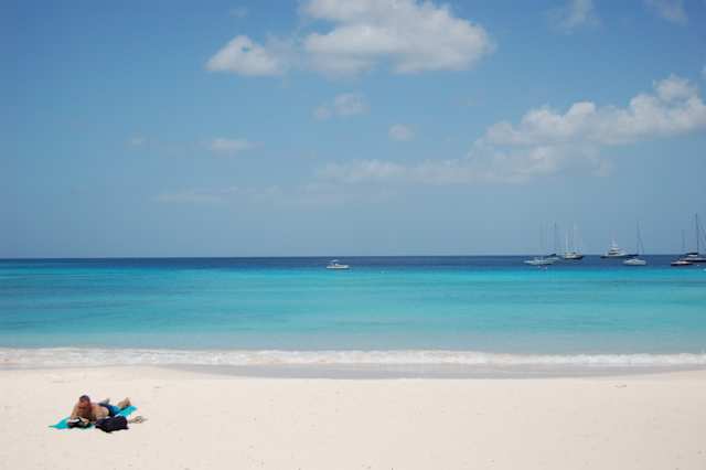 Man sunbathing on beach in front of blue sea at Carlisle Bay, Barbados