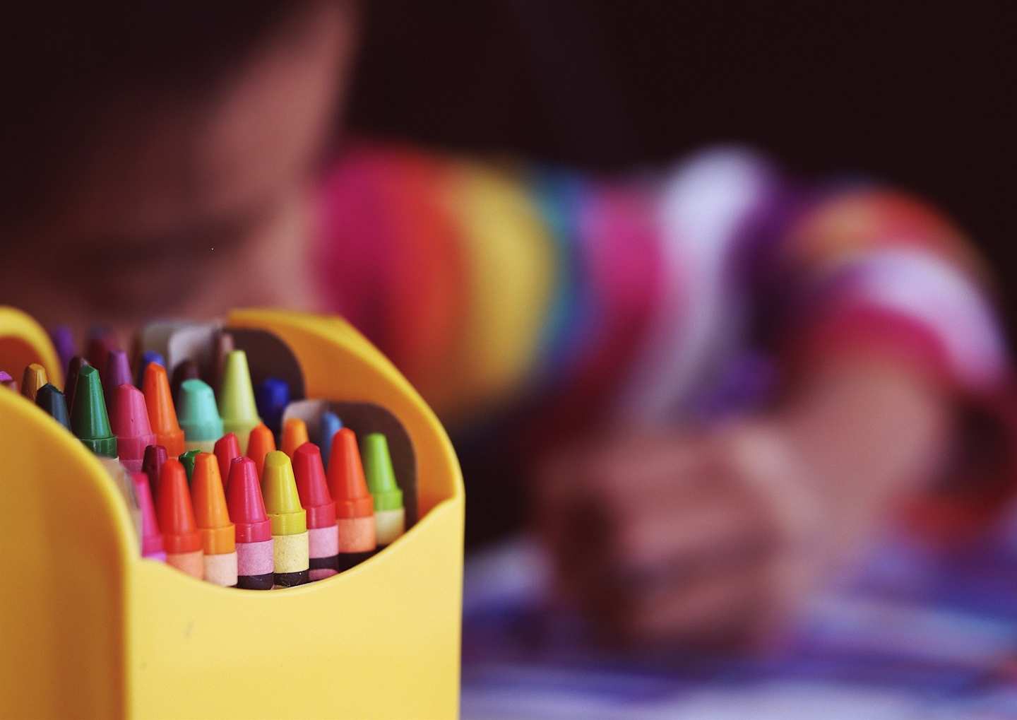 A child colouring using crayons