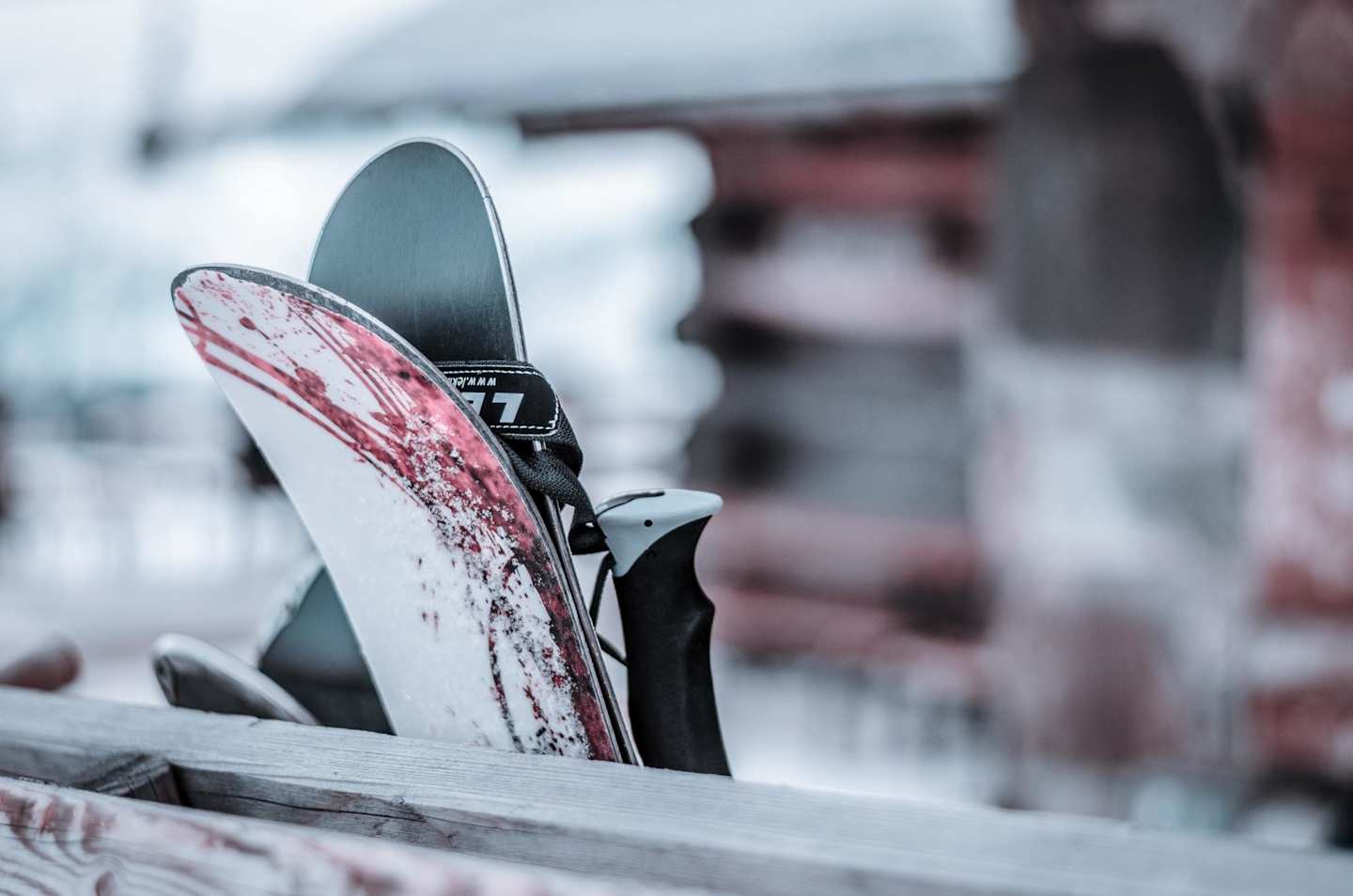 A pair of skis leaning against a wooden fence at a snowy ski resort