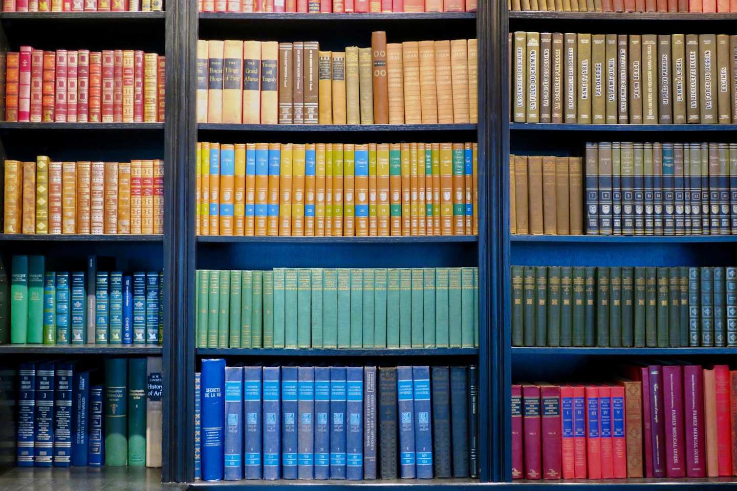 Different coloured books on a white bookshelf