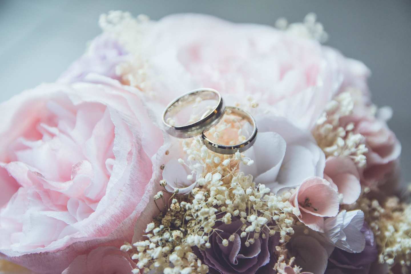 Two wedding rings on top of a bouquet of pink and white flowers