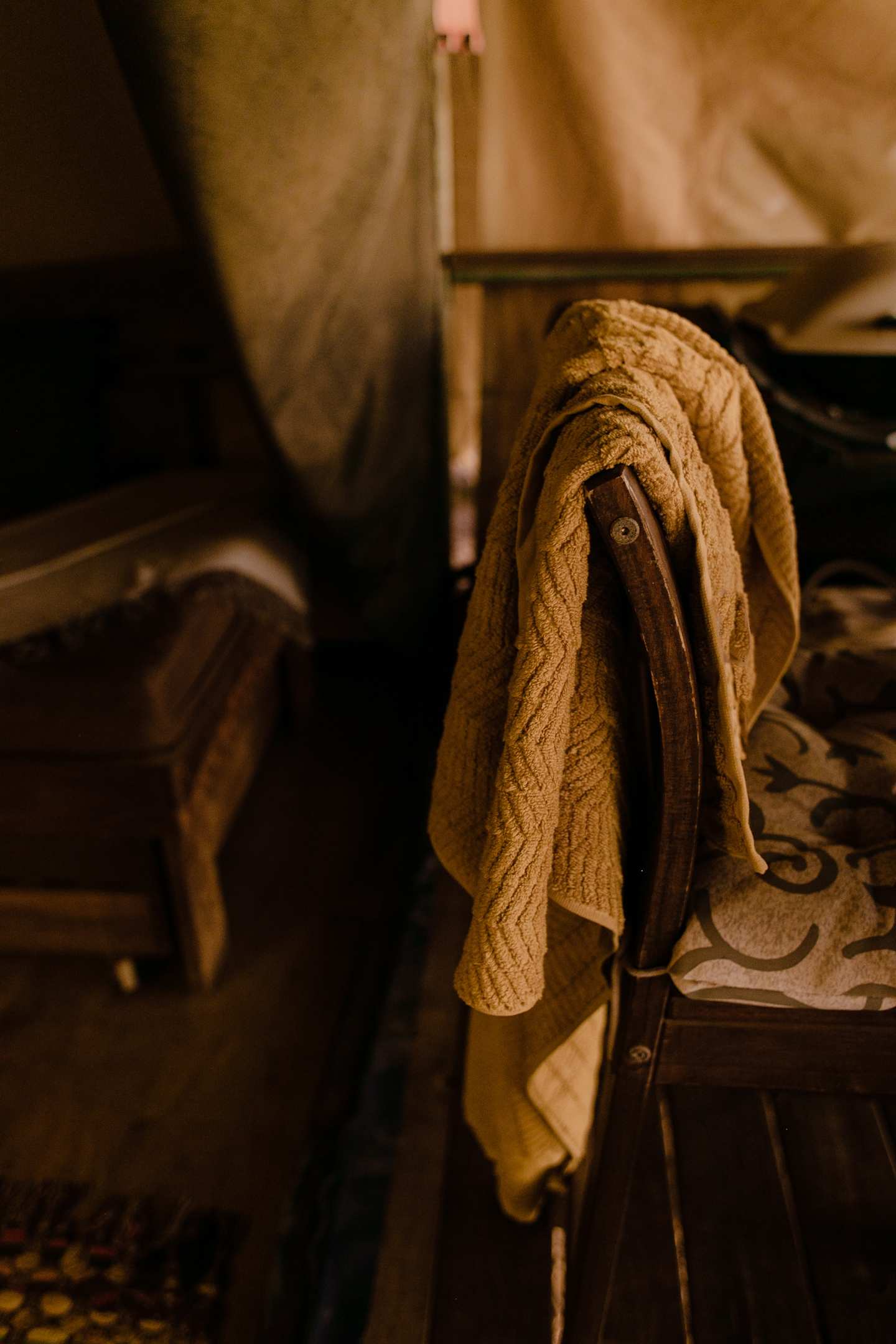 An old chair with a towel over the back, inside an old house