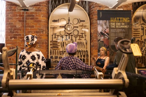 2 people being given a guided tour of the Hat Works.