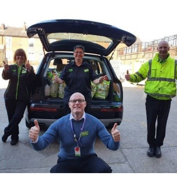 Asda staff in font of an open car boot full of shopping