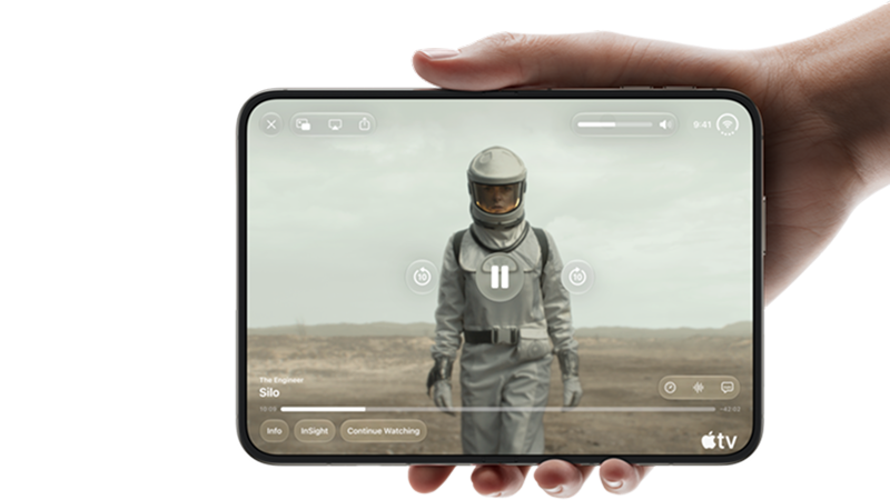En hand håller en iPhone Duo som visar Apple TV-appen med serien Silo, en person i rymddräkt syns på skärmen.